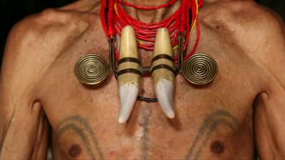 An Indian headhunter showing off his tattoos