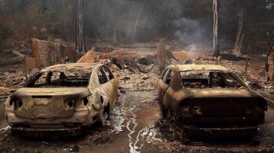 Charred cars parked in front of destroyed home in Northern California.