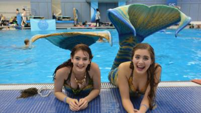 Two mermaid enthusiasts wearing their custom silicon tails