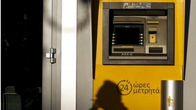 A man cast his shadow on an ATM machine