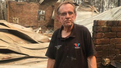 Warren Smith stands amidst the ruins of his house.