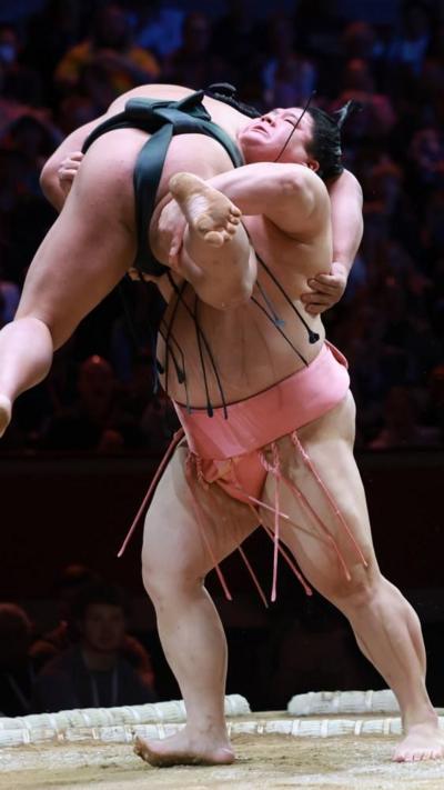Midorifuji (L) is lifted by Ura (R) as they grapple during the Grand Sumo Tournament