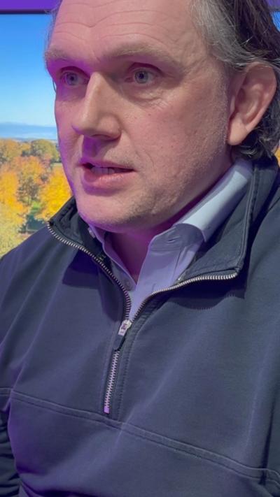 A man with grey hair in a blue shirt and jumper