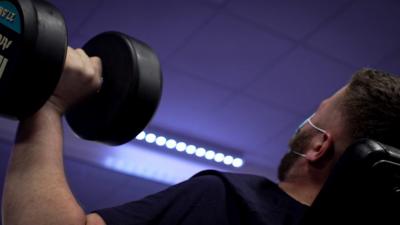 Man in face mask lifting weights