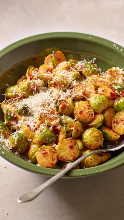 A green bowl containing sprouts topped with parmesan. 