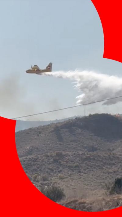 A plane flying over a burning fire and dropping water