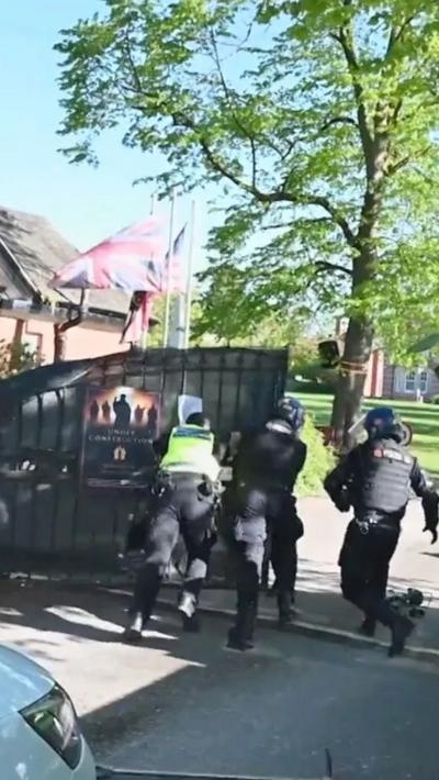 Police in riot gear open a gate during a raid