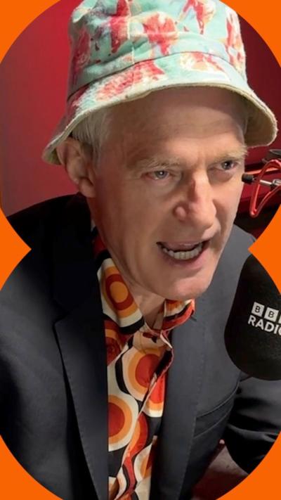 Jeremy Vine wears a colourful shirt, a dark jacket and a bucket hat