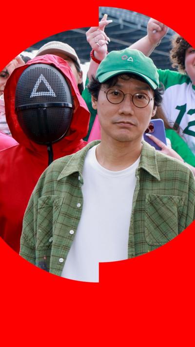 Hwang Dong-hyuk, in green cap and shirt, stands next to a person dressed as a Squid Game red soldier