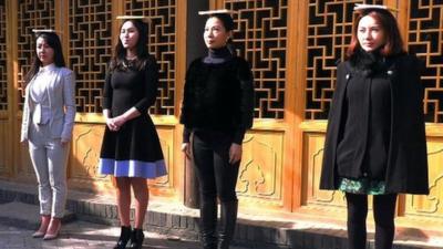 Women practising deportment with books on their head