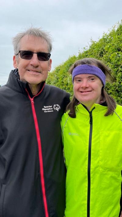 Man in a black running top and woman in lime green running top and purple headband