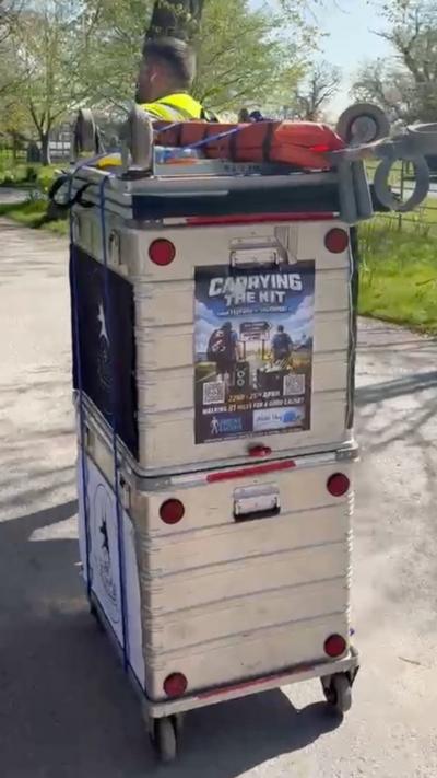 A man pulling a large silver case on wheels containing football club equipment