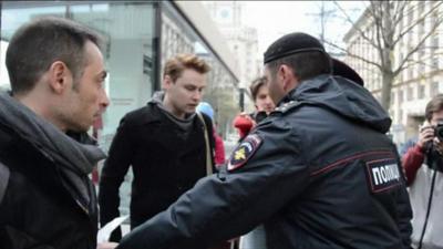 An activist is addressed by police as they argue over the legality of the petition delivery