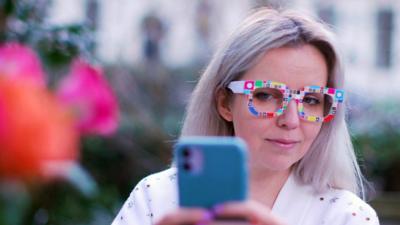 BBC Click reporter Jen Copestake wears a pair of Zozoglass and holds a smartphone