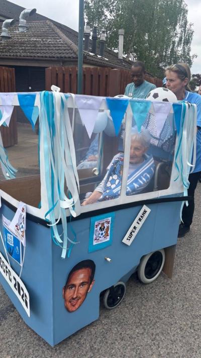 A woman in a wheelchair surrounded by a homemade sky blue bus