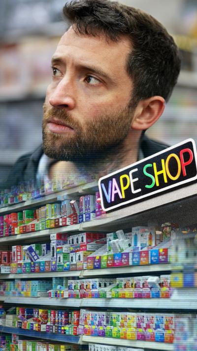 BBC Correspondent David Wallace Lockhart, a man with short brown hair and a beard looks up to the left. A photo of vapes on a shelf is below.