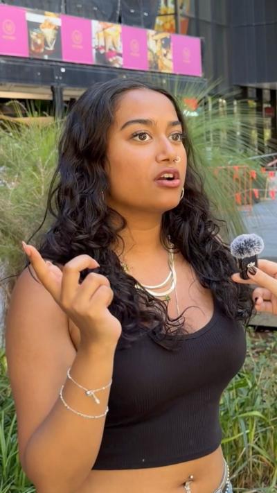 Young women with dark long curly hair wearing a black singlet.