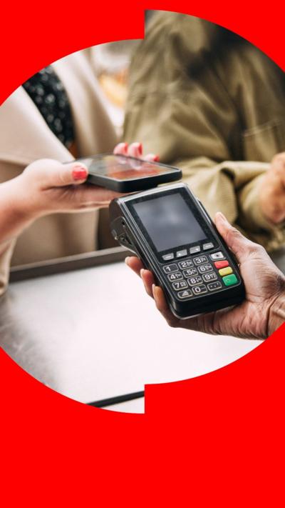 A woman tapping her phone on a card reader to make a contactless payment