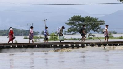 People walk across a bridge inundated with floodwaters in central Myanmar