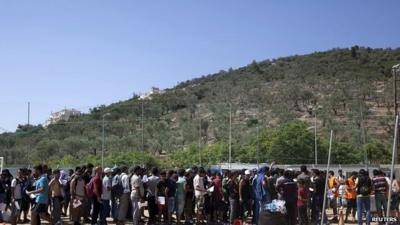 Refugees and migrants line up inside a soccer stadium used as a registration centre on the Greek island of Lesbos