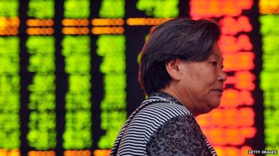 A Chinese investor walks in front of a screen showing share prices at a securities firm in Hangzhou, eastern China