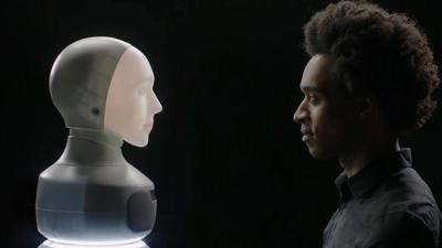 A man looks at an AI robot with a face