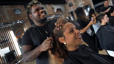 Male hairdresser brushing woman's hair