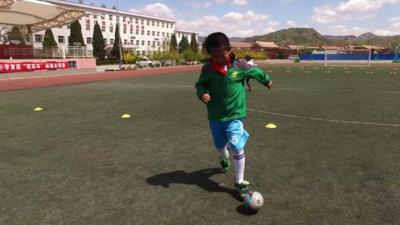 A Chinese boy playing football.