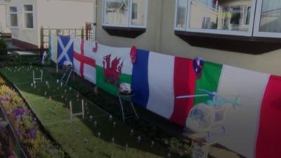 A mini rugby pitch with flags and miniature players