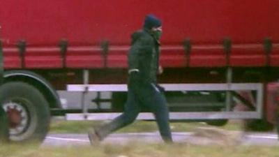 A man with his face covered running to a truck.