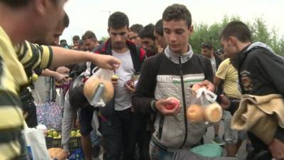 People being given bread rolls and apples