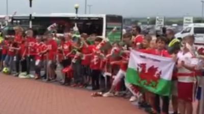Pupils from Cardiff's Ysgol Treganna give a rousing send-off to the Wales team as they depart from Cardiff Airport.