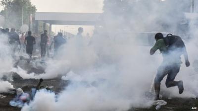 Migrants running from tear gas