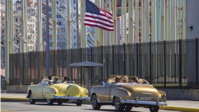 Tourists ride vintage American convertibles as they pass by the United States embassy in Havana, Cuba