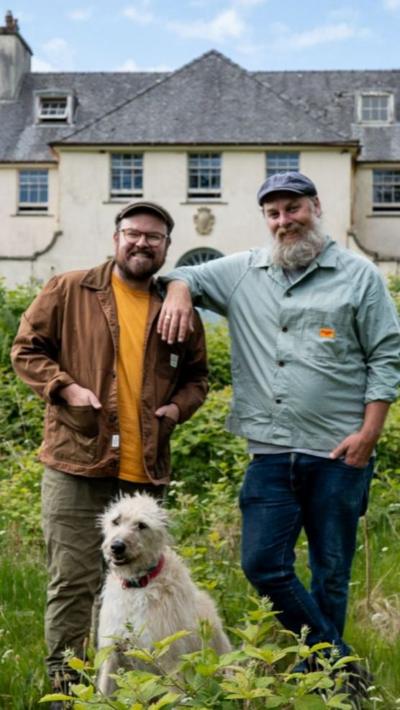 Banjo agus a chèile Ro le cù, agus taigh mòr air an cùlaibh