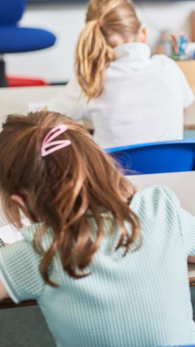 A child sat at a desk seen from the back