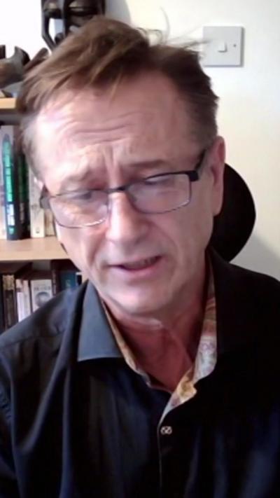 A man with brown hair, glasses and a blue shirt