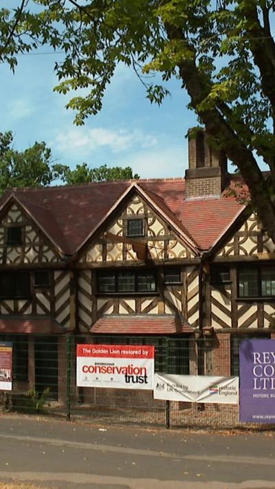 The exterior of a timber framed pub in a park