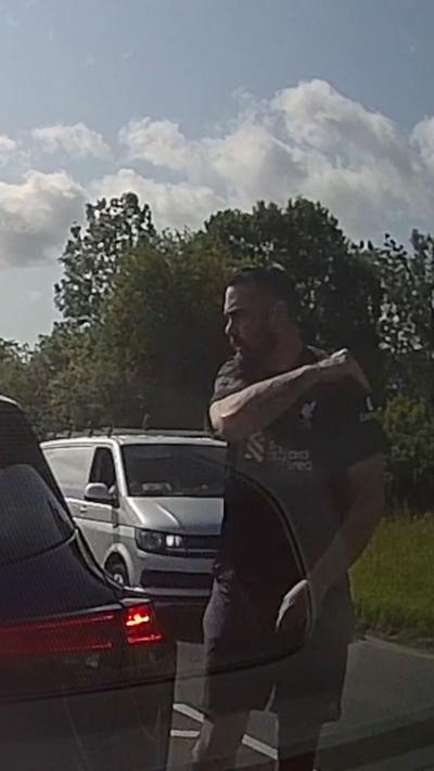 A man captured on a dashcam with his arm up over his shoulder