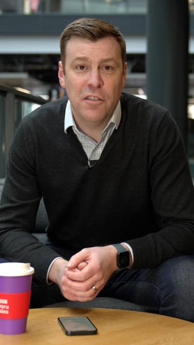 Cemlyn Davies, who has light brown hair, a black jumper and a checked shirt