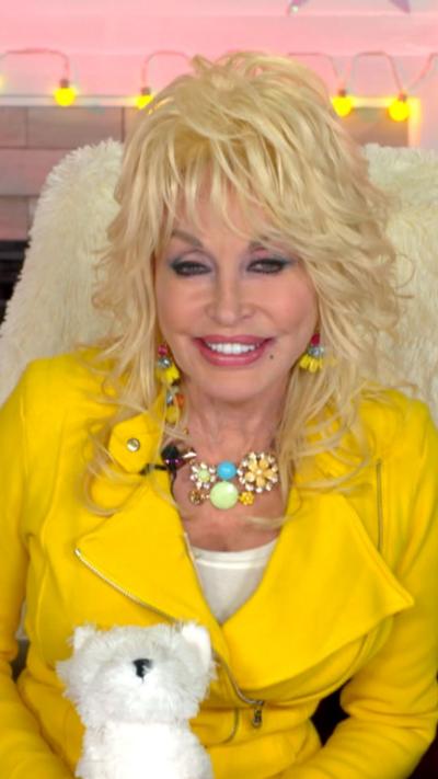Dolly Parton wears bright yellow leather jacket and holds plush dog