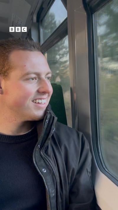 A man looks out the window on a train.
