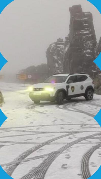 An emergency services car parked across a snow-covered rural road in fog