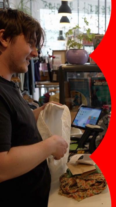 A man stands at the counter of a charity shop store.