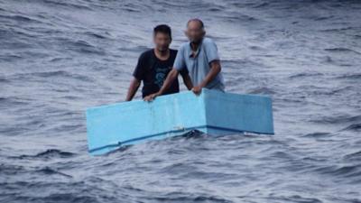 Two men inside a cooling box in the middle of the sea