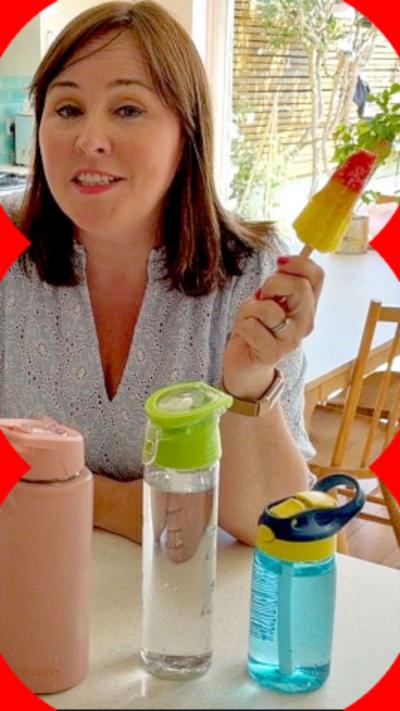Catherine Burne holds an ice lolly in a kitchen with water bottles