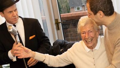 Sally Bloom dances next to a Frank Sinatra tribute singer at her 105th birthday party.