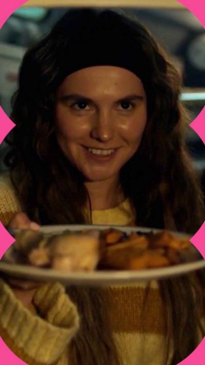 The character Billie looks gleeful as she hands over a plate of food 
