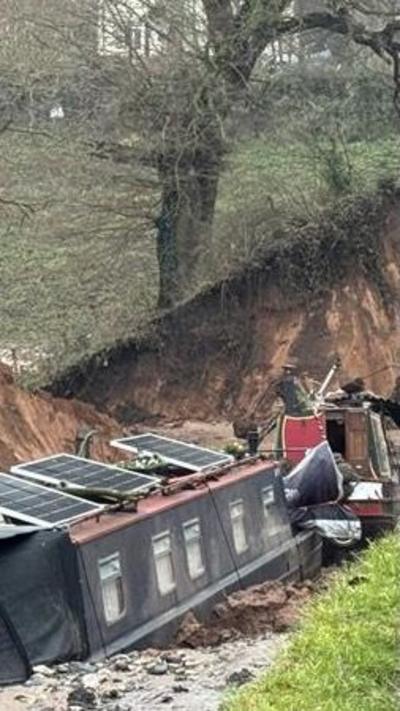 Two narrowboats at the bottom of a canal which has lost its water