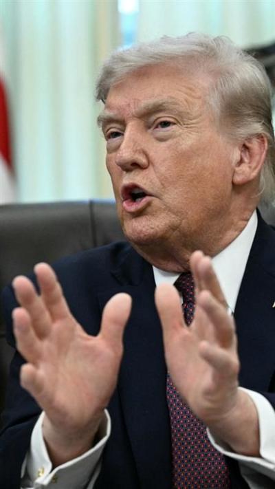 Donald Trump expresses himself using his hands as he speaks to press while in the Oval Office.